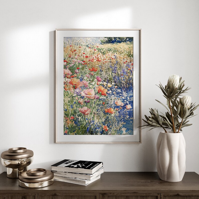 Pode incluir: Uma pintura em aquarela emoldurada de um campo de flores silvestres em tons de rosa, vermelho e azul. As flores est&atilde;o dispostas em uma fileira, com um riacho de &aacute;gua atravessando o centro da imagem.