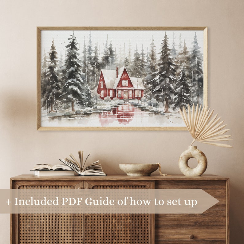 May include: A watercolor painting of a red cabin in a snowy forest. The cabin has a white roof and is surrounded by tall, snow-covered trees. The painting is framed in a light wood frame.