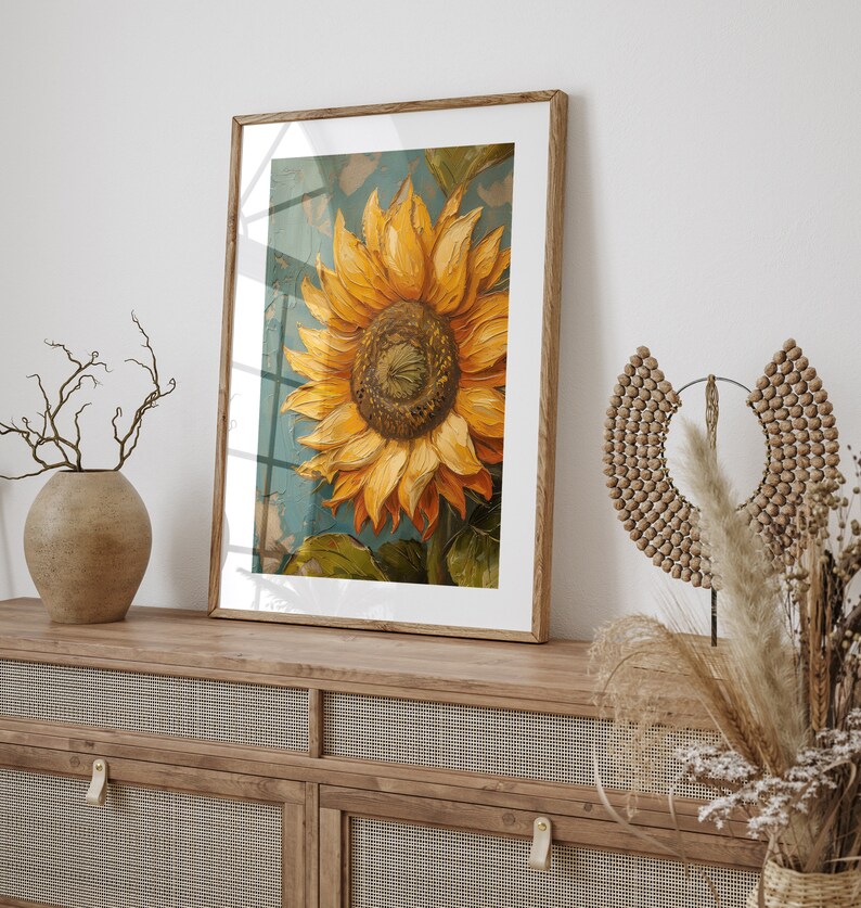 K&ouml;nnte beinhalten: Ein gerahmtes Gem&auml;lde einer Sonnenblume mit gelben Bl&uuml;tenbl&auml;ttern und einer braunen Mitte. Die Sonnenblume befindet sich vor einem blauen und gr&uuml;nen Hintergrund. Der Rahmen ist aus braunem Holz.