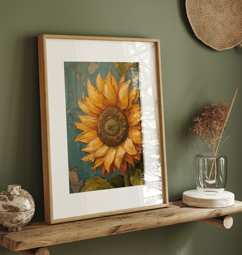 K&ouml;nnte beinhalten: Ein gerahmtes Gem&auml;lde einer Sonnenblume mit gelben Bl&uuml;tenbl&auml;ttern und einer braunen Mitte. Die Sonnenblume ist auf einem blauen Hintergrund mit einem strukturierten Effekt gemalt. Der Rahmen ist aus Holz und hat eine hellbraune Oberfl&auml;che.