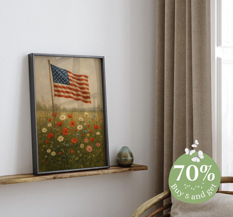 May include: Framed print of the American flag waving in a field of wildflowers. The artwork features a vintage aesthetic with a black frame. The flag has red and white stripes and a blue field of stars. The flowers are red, white, and yellow.