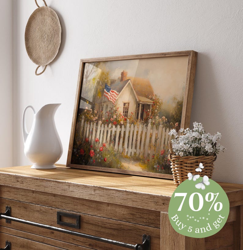 May include: A framed painting of a white cottage with a red, white, and blue American flag waving in the wind. The cottage is surrounded by a white picket fence and a garden of colorful flowers. The painting has a rustic, vintage feel.
