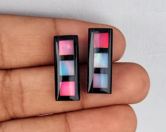 May include: Two rectangular black and white cabochons with a multi-colored opal inlay. The cabochons are set in a black bezel.