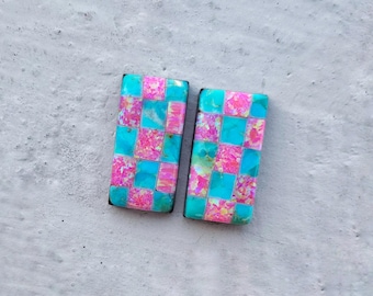 May include: A pair of checkerboard patterned earrings with pink and blue squares. The earrings are made of polymer clay and have a glossy finish.