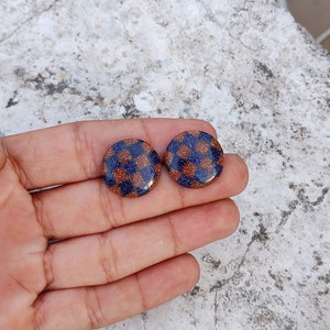 May include: A pair of round, brown and blue checkerboard patterned earrings.