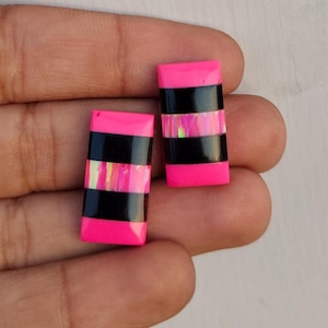 May include: Two pink and black rectangular cabochons with iridescent accents. The cabochons are approximately 2.5 cm long and 1.25 cm wide.
