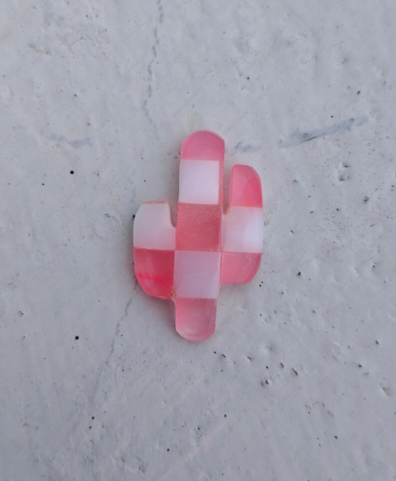 May include: A pink and white checkered cactus shaped resin ornament.
