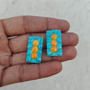 May include: Two rectangular earrings featuring a central vertical row of three smooth, glossy, golden-yellow hexagonal cabochons surrounded by a border of textured, bright turquoise blue stones in a mosaic inlay pattern.