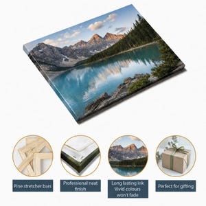 May include: A rectangular canvas print featuring a landscape of turquoise mountain lake water reflecting snow-capped peaks and a dense pine forest. The product includes pine stretcher bars, a neat finish, and long-lasting ink.