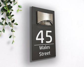 May include: A black house number sign with a built-in light. The sign has white lettering and reads "45 Wales Street".