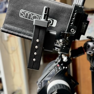 Könnte beinhalten: Schwarzes Video-Kamerarigg mit einer Matte Box und einem Monitor. Auf der Matte Box steht in Weiß der Text "smallHD.com". Die Kamera hat ein ARRI-Objektiv und ist auf einem Trägersystem montiert. Das Rig ist schwarz und hat verschiedene Einstellknöpfe und Schrauben.