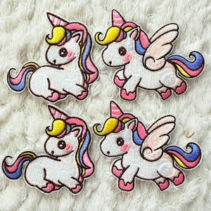 Puede incluir: Cuatro parches bordados de unicornios. Cada unicornio es blanco con una melena y cola rosa, amarilla y azul. Dos unicornios tienen alas. Los parches tienen pezuñas rosas y un cuerno rosa.