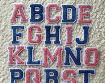 May include: A set of 26 felt alphabet letters in pink and blue. The letters are uppercase and have a white outline.
