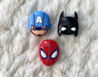May include: Three superhero character buttons. A blue Captain America button, a black Batman button, and a red Spiderman button.