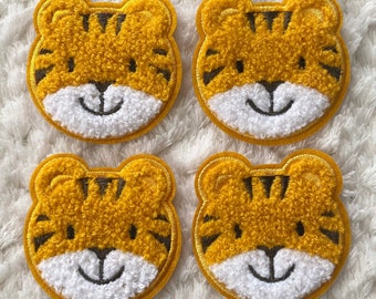 May include: Four yellow and brown fuzzy tiger face patches with white smiling mouths and black eyes.