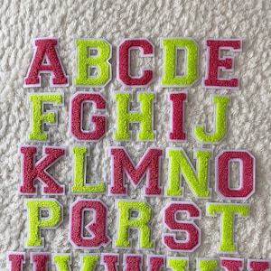 May include: A collection of colorful, embroidered alphabet letters. The letters are in a varsity style, with a fuzzy texture. The letters alternate between red and green, with a white border. The letters are arranged in alphabetical order.