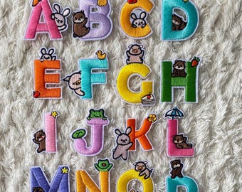 May include: A set of 26 colorful embroidered iron-on patches featuring the alphabet with cute animal illustrations. Each letter is surrounded by a white outline and features a different animal design.