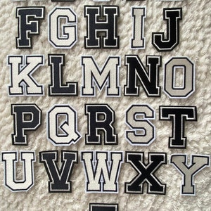 Könnte beinhalten: Ein Satz von 26 Bügelbuchstaben in Schwarz und Weiß. Die Buchstaben sind in einer klassischen Schriftart im College-Stil gehalten. Die Buchstaben sind in alphabetischer Reihenfolge angeordnet.