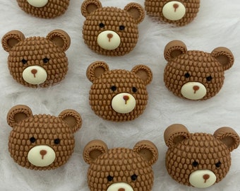 May include: Ten brown bear-shaped buttons with white faces and black eyes. The buttons are textured and have a 3D effect.