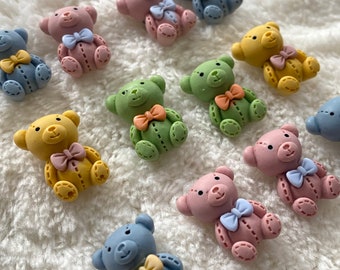 May include: Assortment of small, colorful teddy bear buttons with stitched details and bows. The buttons are made of polymer clay and come in shades of blue, green, pink, and yellow.