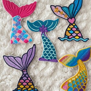 May include: Six embroidered mermaid tail patches in various colors, including pink, blue, purple, green, and yellow. Each patch features a different scale pattern and a unique design.
