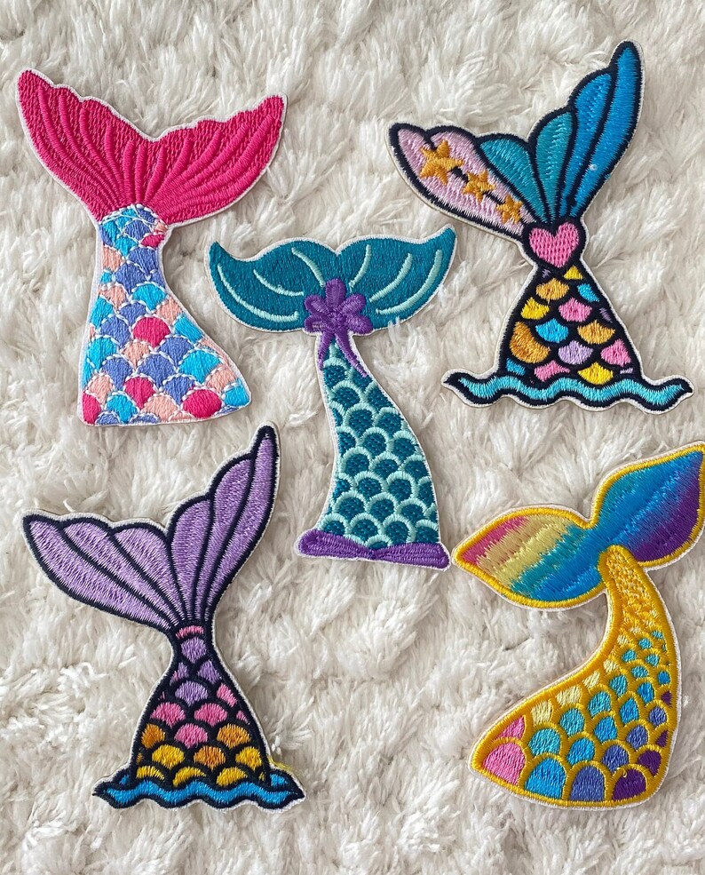 May include: Six embroidered mermaid tail patches in various colors, including pink, blue, purple, green, and yellow. Each patch features a different scale pattern and a unique design.