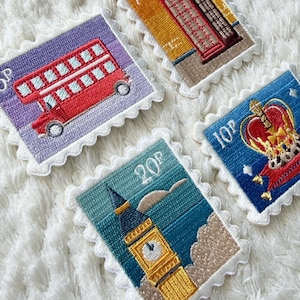 May include: Embroidered patches in the style of postage stamps, featuring iconic British imagery. Designs include a red double-decker bus, a red telephone box, Big Ben, and a royal crown. Each patch has a white scalloped border.