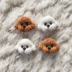 May include: Four small dog figurines, two are brown and two are white. The figurines are made of a textured material and have small black eyes and noses.