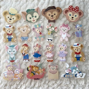 以下が含まれることがあります： 様々なクマと猫のデザインが特徴の、カラフルな漫画のキャラクターのステッカーのコレクション。ステッカーは、さまざまな衣装とポーズのキャラクター、一部はアクセサリーを持っています。ステッカーは白いテクスチャのある表面に配置されています。