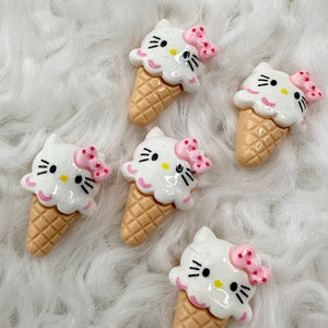 May include: Six white and pink Hello Kitty ice cream cone charms. The cones are a light brown color and have a waffle pattern. The Hello Kitty faces are white with black eyes and whiskers. Each Hello Kitty has a pink bow on top of its head.