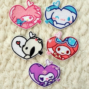 Puede incluir: Cinco parches bordados en forma de corazón con personajes de dibujos animados en varios colores. Los parches incluyen diseños rosas, azules, negros, rojos y morados. Cada parche tiene un borde blanco.