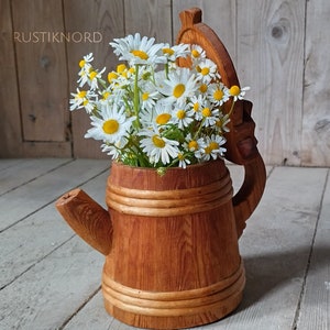 Peut inclure: Une chope à bière en bois avec un couvercle, décorée d'un bouquet de marguerites blanches.