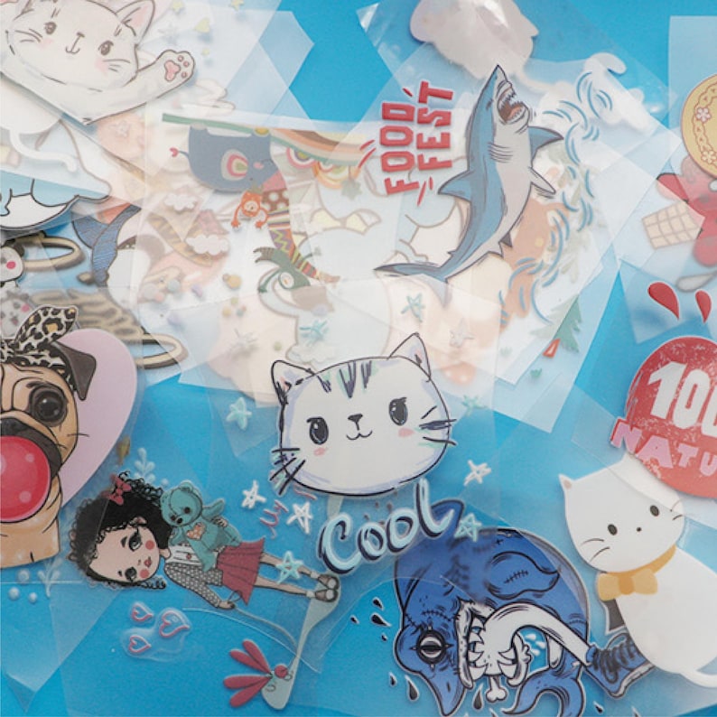 May include: A collection of colourful iron-on patches featuring various designs, including a cat, a pug, a shark, and a monster. The patches are on a blue background and have a variety of text, including "Food Fest" and "Cool".