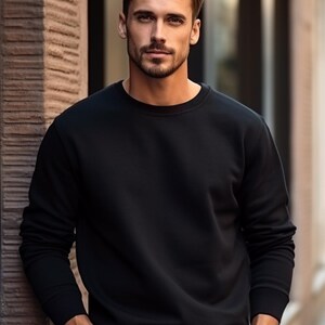 May include: A man wearing a black crew neck sweatshirt with his hands in his pockets.