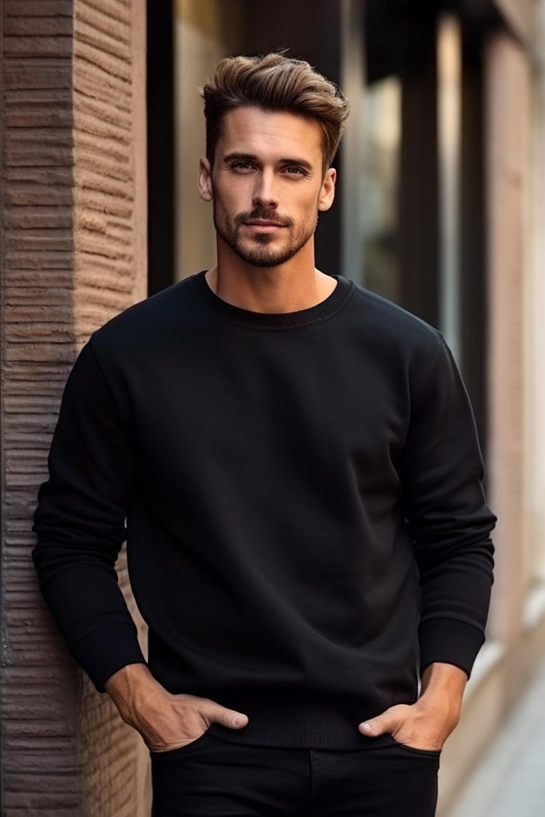 May include: A man wearing a black crew neck sweatshirt with his hands in his pockets.