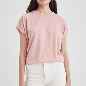 K&ouml;nnte beinhalten: Ein rosa T-Shirt mit kurzen &Auml;rmeln und einem dezenten Glitzereffekt. Das Shirt hat eine lockere Passform und einen runden Ausschnitt.