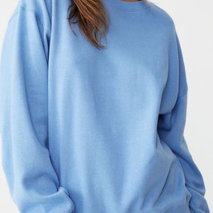 Pu&ograve; includere: Una felpa oversize di colore azzurro chiaro con maniche lunghe e collo rotondo.