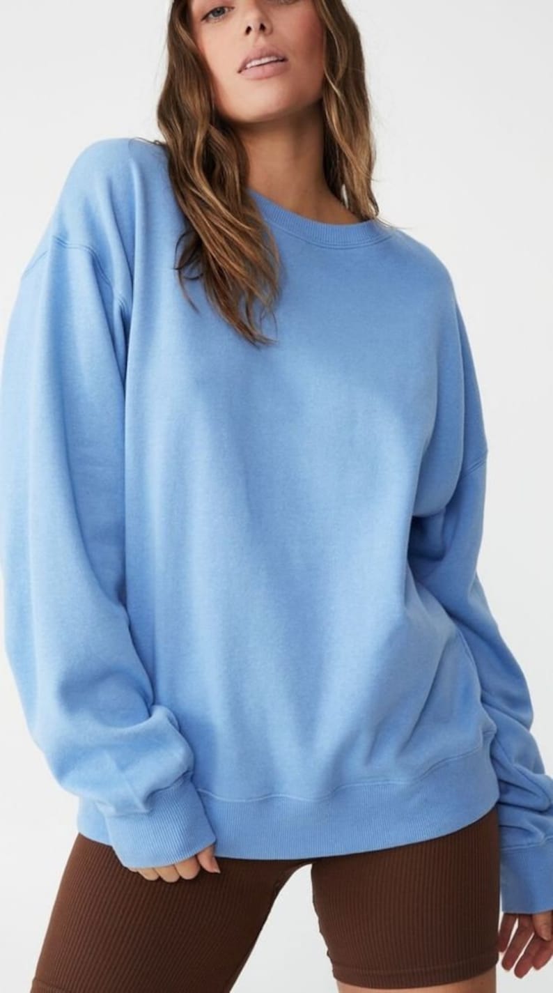Pu&ograve; includere: Una felpa oversize di colore azzurro chiaro con maniche lunghe e collo rotondo.