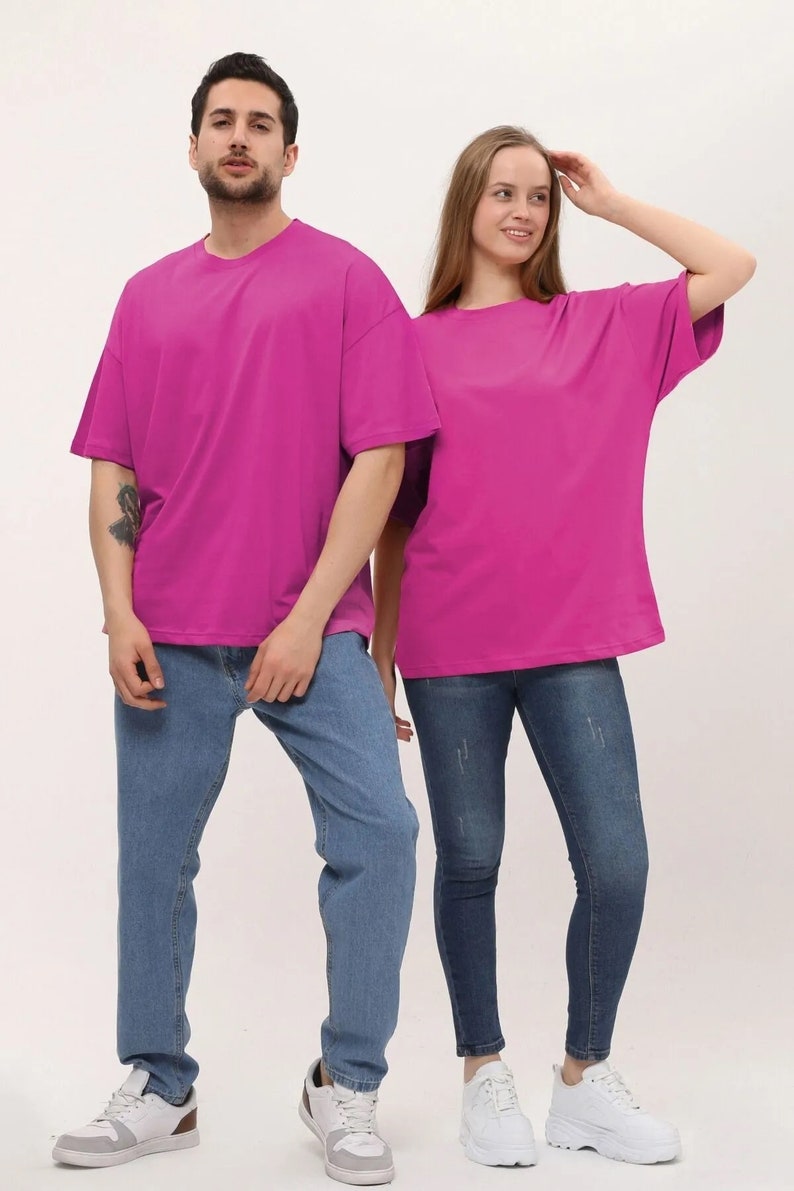 Puede incluir: Dos personas con camisetas rosas de gran tama&ntilde;o a juego y pantalones vaqueros azules. Ambos llevan zapatillas blancas.