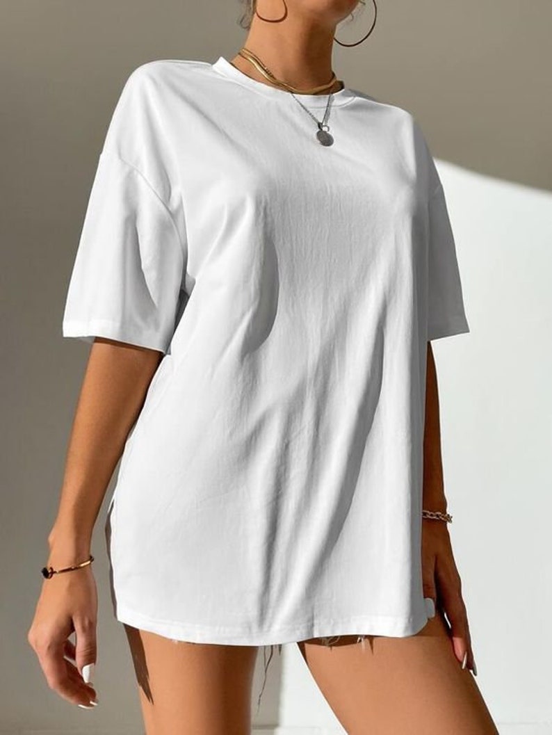 May include: An oversized white t-shirt with short sleeves. The shirt is made from a soft, comfortable fabric and has a relaxed fit.
