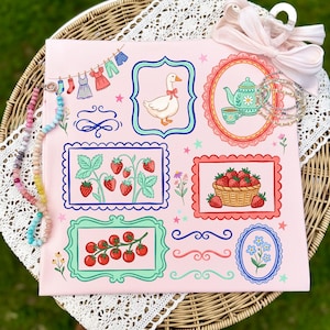 Könnte beinhalten: Ein rosa Dekorstoff mit gerahmten Illustrationen einer Gans, Erdbeeren, Tomaten und einer Teekanne. Das Design umfasst eine Wäscheleine mit Miniaturkleidung, dekorative Wirbel und einen Korb mit Erdbeeren. Eine Perlenkette und ein rosa Band sind ebenfalls vorhanden.