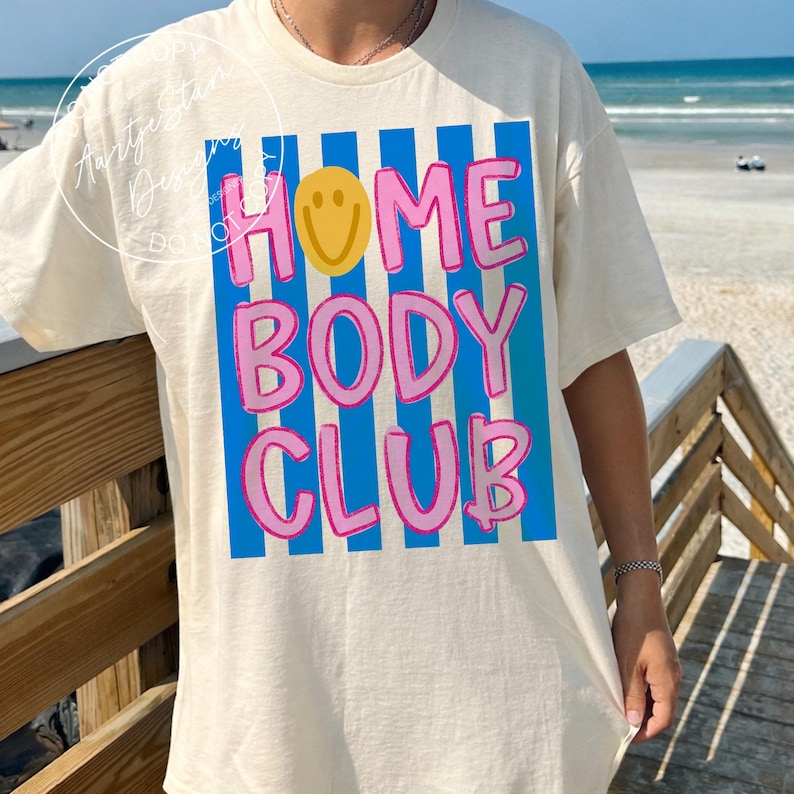 Homebody Club shirt PNG retro Y2K bold bubble letter smiley face blue stripe pink text, on Comfort Colors ivory oversized tee worn beach boardwalk, soft girl VSCO girl lazy girl era funny saying shirt spring break Florida couch potato humor, for DTF transfers, sublimation shirts, tumblers, apparel printing.