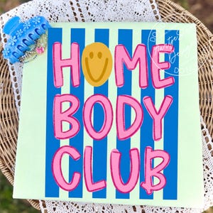 Homebody Club shirt PNG retro Y2K bold bubble letter smiley face blue stripe pink text, on mint green tee flatlay blue claw clip styling, coquette aesthetic teacher squad soft girl sassy funny saying shirt lazy girl era procrastination humor, for DTF transfers, sublimation shirts, tumblers, apparel printing.