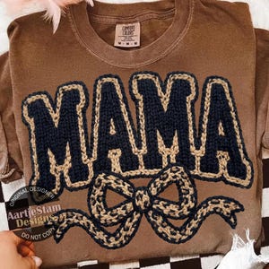 Könnte beinhalten: Braunes Comfort Colors T-Shirt mit dem Wort "MAMA" in Marineblau, umrandet in Beige, und einem beigen und marineblauen Schleifendesign. Das Shirt hat einen Rundhalsausschnitt und ein Etikett mit der Aufschrift "Comfort Colors". Größe M.