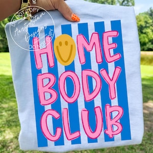 Homebody Club shirt PNG retro Y2K bubble letter smiley face blue stripe hot pink bold text, on ash gray tee held outdoor, lazy girl era couch potato sarcastic funny saying shirt VSCO girl soft girl homebody procrastination humor, for DTF transfers, sublimation shirts, tumblers, apparel printing.