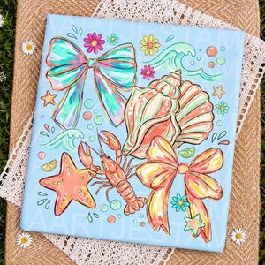 Könnte beinhalten: Ein hellblauer rechteckiger Druck mit einer farbenfrohen Illustration eines Hummers, eines Seesterns, zwei großer Schleifen, Muscheln, kleiner Blumen und Wasserwellen. Das Design enthält lebhafte Töne in Pink, Gelb, Türkis und Orange.