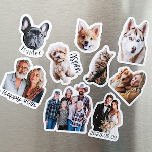 May include: A set of nine personalized magnets featuring photos of people and pets. The magnets include a couple, a family, a dog, a cat, and a group of children. The magnets are decorated with text, including "Happy 40th", "Hunter", "Aspen", and "2023.09.09".