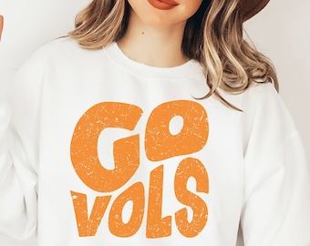 May include: White sweatshirt with orange text that says "GO VOLS" in a retro font.