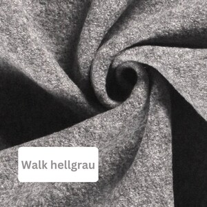 May include: Close-up of a light gray fabric with a soft, textured surface. The fabric is folded and twisted, creating a swirling pattern.