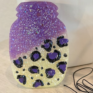 May include: A purple and yellow glitter jar with a black and purple leopard print design.